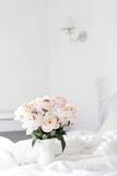 Bouquet of pink peonies on white bed linen. Modern interior in the bedroom. Wedding and festive style.