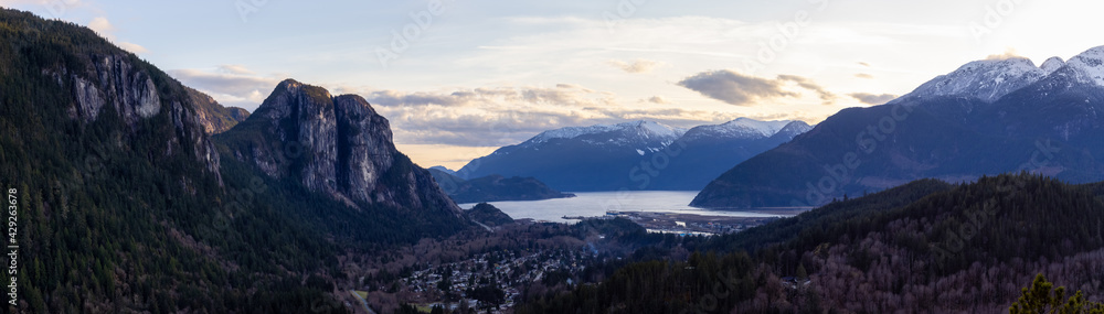 Squamish, North of Vancouver, British Columbia, Canada. Panoramic View from the top of the Mount Crumpit of a small town surrounded by Canadian Mountain Landscape. Spring Sunset