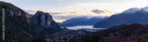 Squamish, North of Vancouver, British Columbia, Canada. Panoramic View from the top of the Mount Crumpit of a small town surrounded by Canadian Mountain Landscape. Spring Sunset