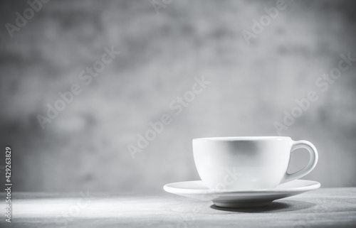 Tea cup on gray table and background, front view. White teacup. Blank free space for your advertising or text