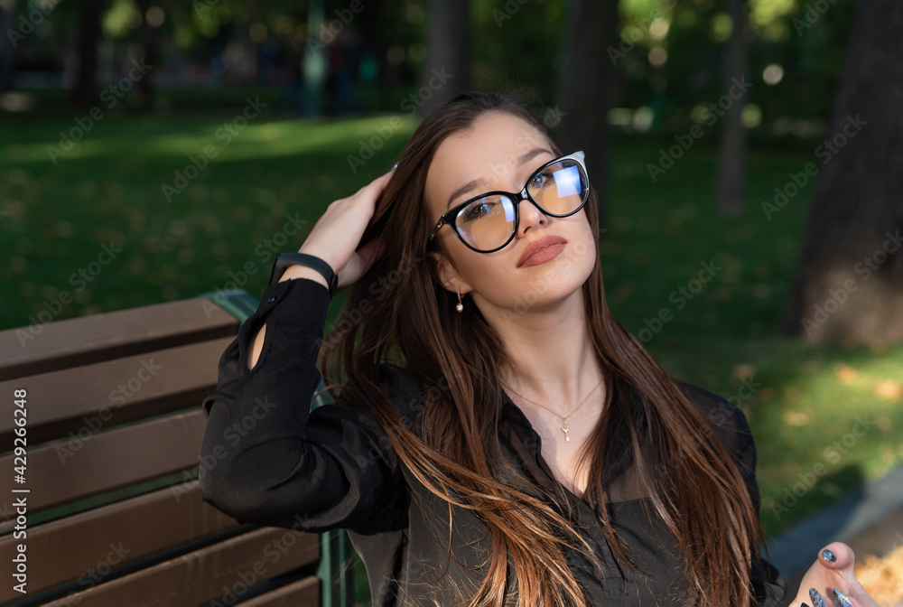 Portrait of beautiful young brunette woman with glasses in park. Charming stylish woman rest outdoor Portrait of beautiful young brunette woman with glasses in park. Charming stylish woman rest outdoor