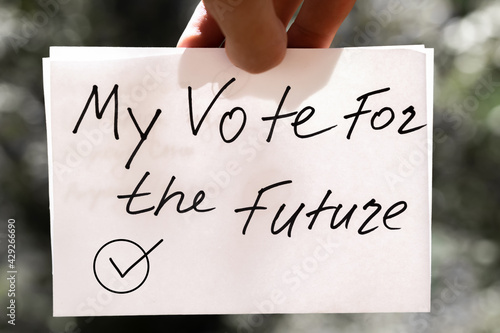 Male hand holds white paper with "Vote" inscription. Vote and Make a choice image concept.