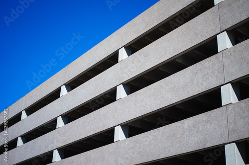 Facade of a parking garage with the sun shining on it and a blue sky