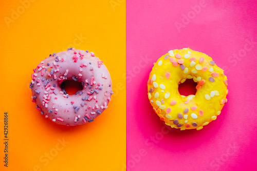 Two sugar glazed donuts on colorful background.