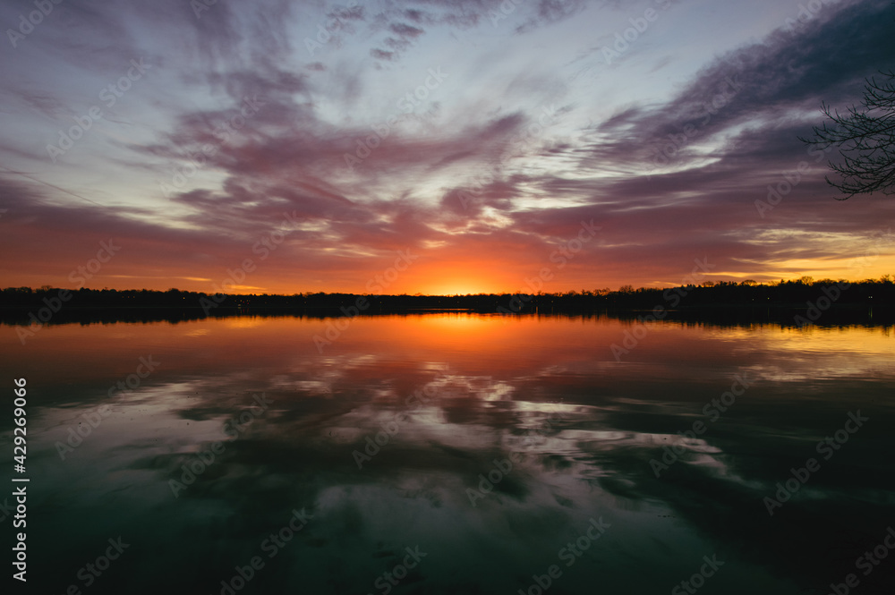 Colorful sunset over lake with beautiful clouds and reflection