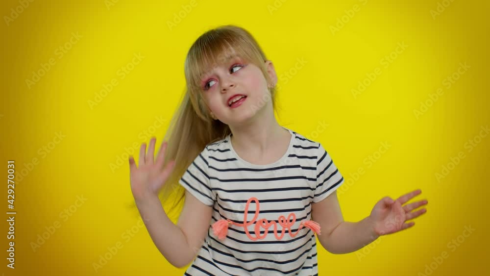 Little teen kid child girl in striped t-shirt listening music dancing disco fooling around having fun expressive gesticulating hands on yellow studio background. Young children lifestyle emotions Little teen kid child girl in striped t-shirt listening music dancing disco fooling around having fun expressive gesticulating hands on yellow studio background. Young children lifestyle emotions