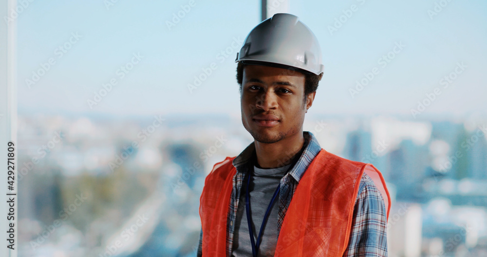 Afro-american civil engineer working on design plan construction building inside office. Portrait of successful young foreman architect posing for camera. Afro-american civil engineer working on design plan construction building inside office. Portrait of successful young foreman architect posing for camera.