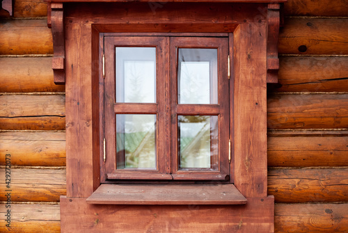 A window with a wooden profile in a house made of beams.