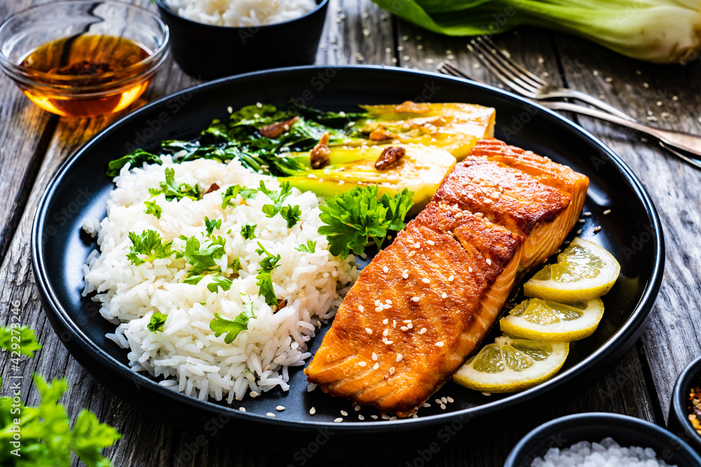 Fried salmon steak with lemon, jasmine rice and fried pak choi cabbage served on wooden table
Fried salmon steak with lemon, jasmine rice and fried pak choi cabbage served on wooden table