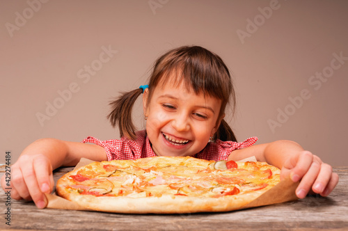 Huppy cute little girl with pizza. Child having fun eating dinner. Horizontal image.