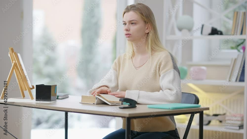 Concentrated blind young woman reading braille book at home. Portrait of beautiful disabled Caucasian lady enjoying hobby indoors. Disability and special needs concept Concentrated blind young woman reading braille book at home. Portrait of beautiful disabled Caucasian lady enjoying hobby indoors. Disability and special needs concept