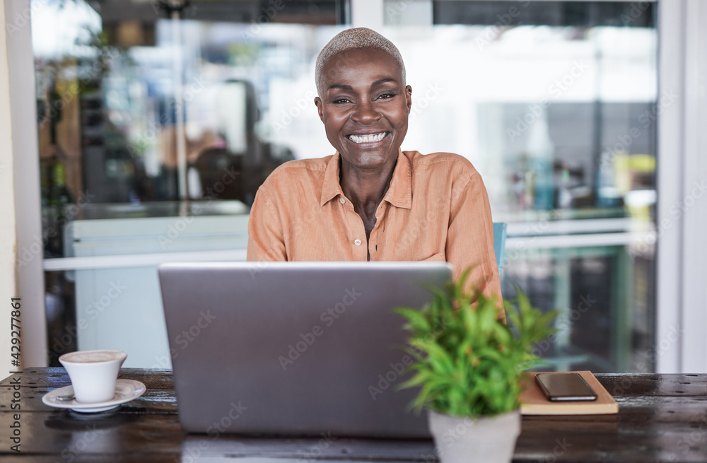 Beautiful mature african woman sitting in a bar outdoor and working with laptop - Black woman looking in camera and smiling Beautiful mature african woman sitting in a bar outdoor and working with laptop - Black woman looking in camera and smiling