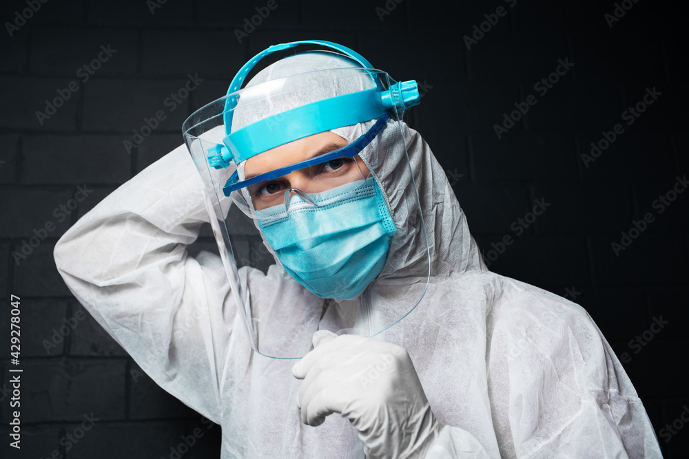 Close-up portrait of young doctor man wearing PPE suit against coronavirus and covid-19. Background of black brick wall. Close-up portrait of young doctor man wearing PPE suit against coronavirus and covid-19. Background of black brick wall.