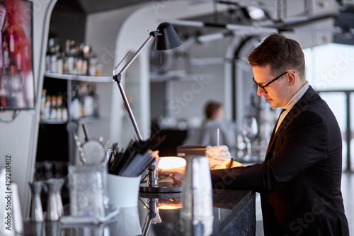 Side view on concentrated focused man taking notes while standing in restaurant cafe