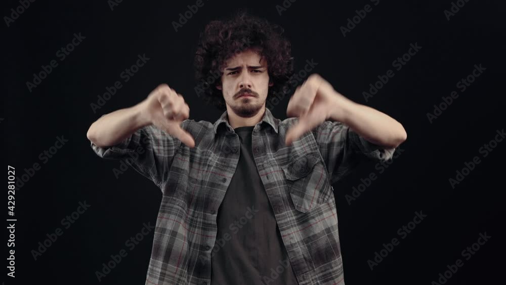 The charismatic young man, frowning, asks what, shows his disapproval through the sign of dislike. Isolated on black background, Concept of life. People's emotions. 4k portrait The charismatic young man, frowning, asks what, shows his disapproval through the sign of dislike. Isolated on black background, Concept of life. People's emotions. 4k portrait