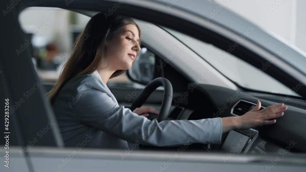 elegant woman in a suit sitting behind the wheel strokes the car dashboard and smiles elegant woman in a suit sitting behind the wheel strokes the car dashboard and smiles