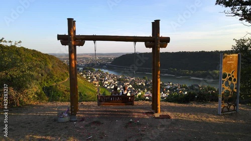 Couple sits on swing looking at landscape. Located in Leutesdorf, Germany. photo