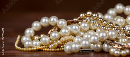 White and gold pearls, female gift jewelry necklace close-up on brown background. Web banner.