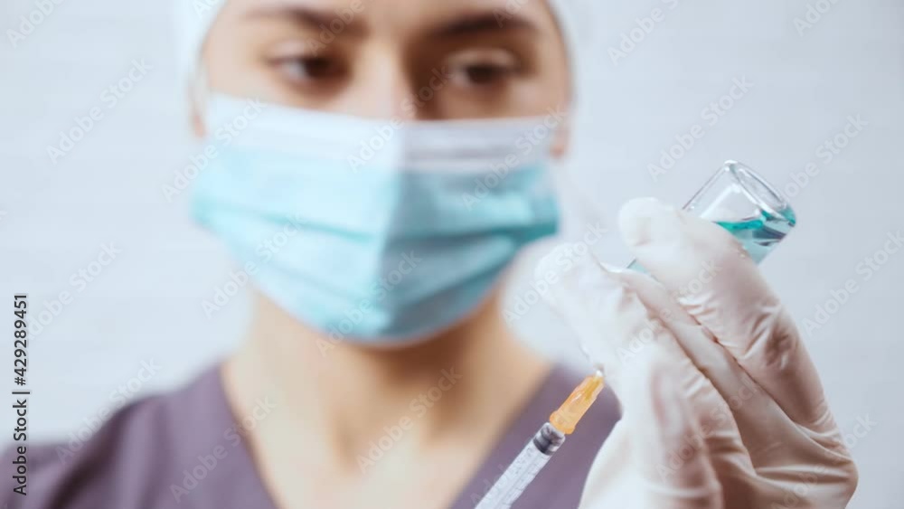 Nurse with protective mask, cap and white rubber gloves in hospital with syringe with medicine. Concept of covid-2019. Nurse with protective mask, cap and white rubber gloves in hospital with syringe with medicine. Concept of covid-2019.