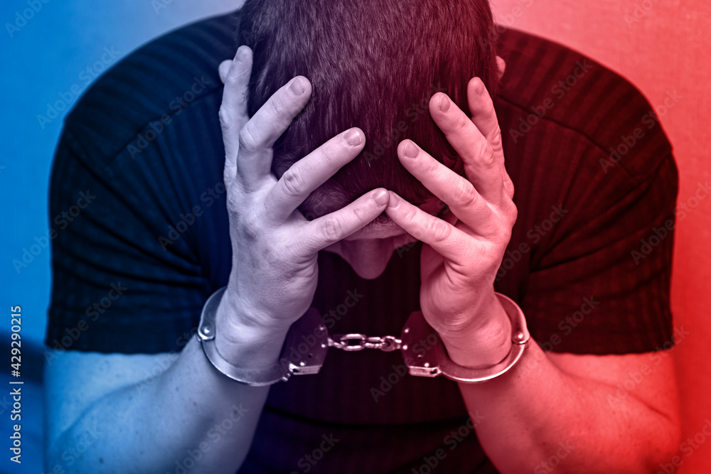 Φωτογραφία Criminal in handcuffs in the light of the police signal lights