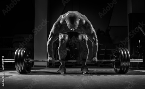 Muscular man is unbending with a barbell in his hands. Deadlift. Bodybuilding and powerlifting concept. photo