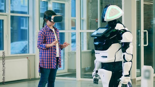 Teenage girl in VR-glasses and a cyborg chatting with her photo