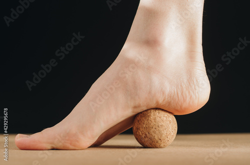 Isolated close up of foot on cork ball for plantar fascia MFR on black background.  photo