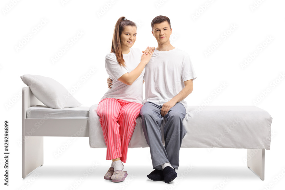 Young couple in pajamas sitting on a bed Young couple in pajamas sitting on a bed