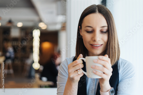 Attractive female with cute smile having a coffee while relaxin in a break