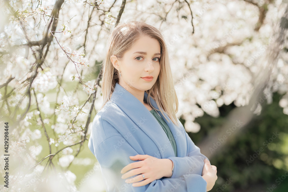 Beautiful young blonde woman standing near the apple tree Beautiful young blonde woman standing near the apple tree