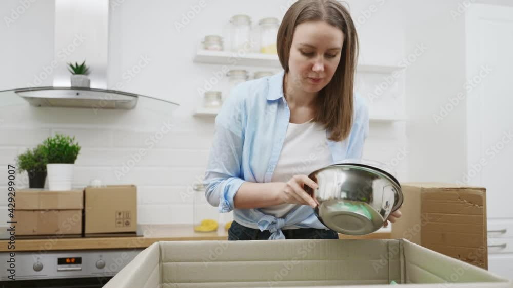 Woman arranges kitchen utensils after moving to new apartment. Woman arranges kitchen utensils after moving to new apartment.