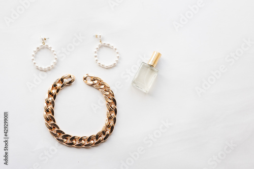 White and gold jewelry collection: chain, pearl earrings, hairpin, perfume. Jewelry for a woman. High quality photo