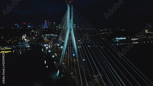 Illuminated Holy Cross Bridge (Most Swietokrzyski) at night. Elevated view of cable-stayed bridge over river. Night Warsaw city panorama. 