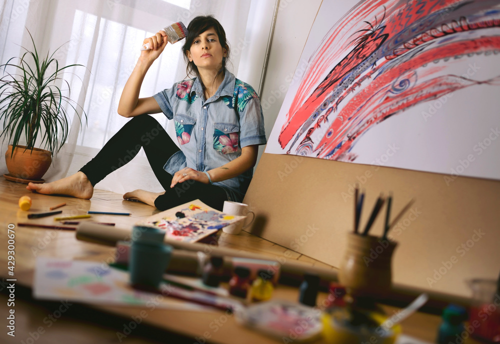 Fototapeta premium Portrait of female artist with paint brush in studio. Creative activity and inspiration concept. Talented people concept.