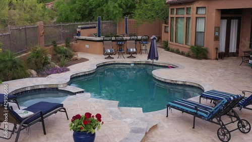 A 4k high definition aerial clip of a desert landscaped travertine tile pool and BBQ. in an Arizona backyard.