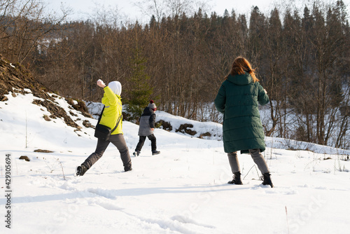 Young people and children play outdoors in winter on the snow in the highlands.