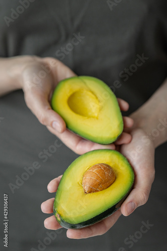 women's hands holding avocado, Caucasian woman in dark t-shirt, kitchen, cooking chef, ripe and delicious avocado, healthy and healthy food, raw fruits and vegetables vegan vegetarian