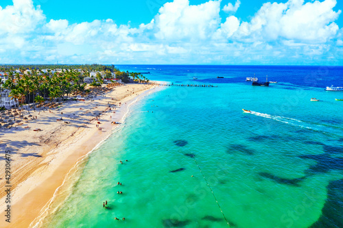 Fototapeta Naklejka Na Ścianę i Meble -  Beach vacation and travel background. Aerial drone view of beautiful atlantic tropical beach with straw umbrellas, palms and boats. Bavaro beach, Punta Cana, Dominican Republic.