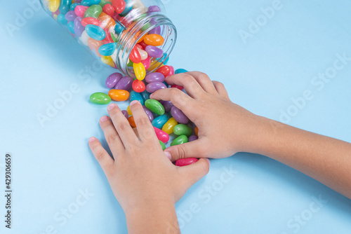 Child's hand holding several Jelly Beans over blue background
