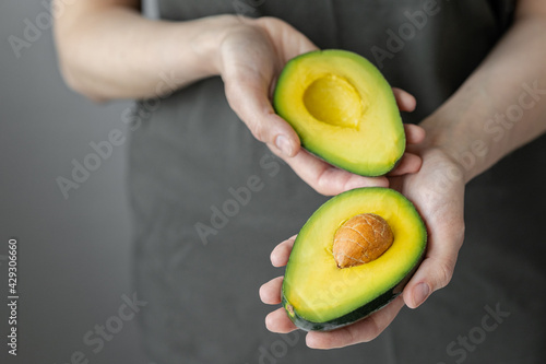 women's hands holding avocado, Caucasian woman in dark t-shirt, kitchen, cooking chef, ripe and delicious avocado, healthy and healthy food, raw fruits and vegetables vegan vegetarian