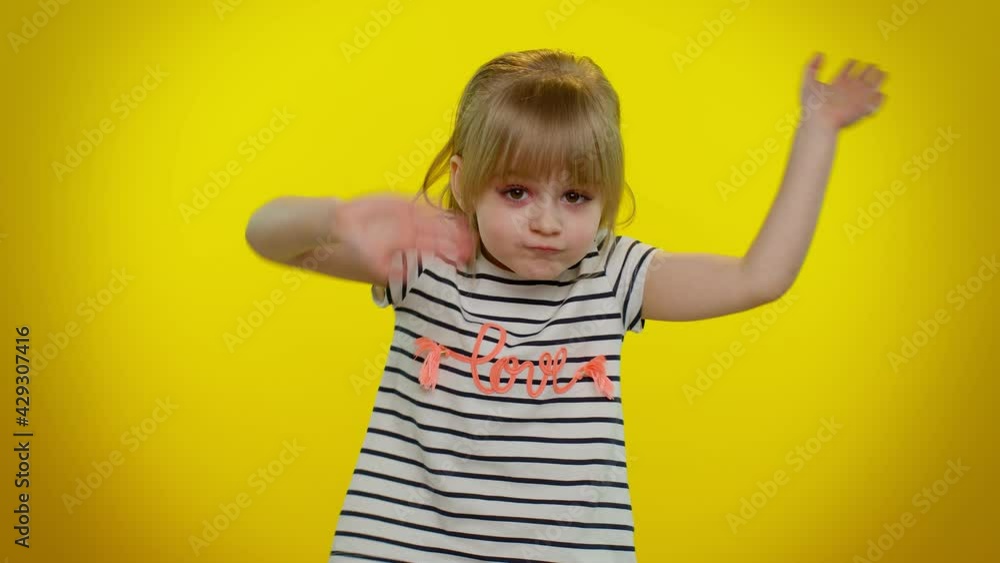 Portrait of funny playful blonde child girl 5-6 years old in striped t-shirt scream with hand near mouth waving and greeting with hand as notices someone on yellow wall background. Teen kid children Portrait of funny playful blonde child girl 5-6 years old in striped t-shirt scream with hand near mouth waving and greeting with hand as notices someone on yellow wall background. Teen kid children