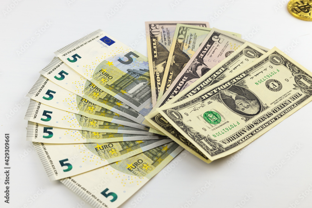 A stack of American dollars banknotes and five euro banknotes on a white background. Close-up, selective focus. A stack of American dollars banknotes and five euro banknotes on a white background. Close-up, selective focus.