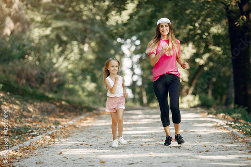 Mother with daughter doing sport in a summer park