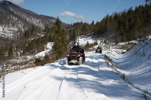 A group of young people ride ATVs in the snow-capped mountains. Carpathians. Ukraine.