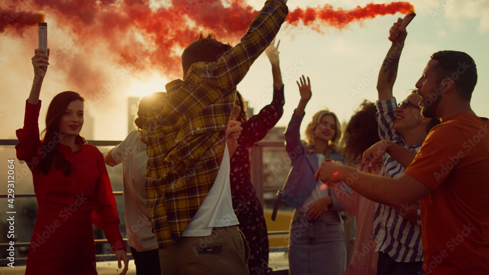 Partying friends having fun with smoke bombs at rooftop. Friends enjoying party