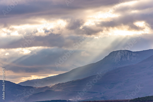 Southern coast of Crimea at sunset in winter. Sunset rays of the sun break through the clouds. Mountains, coast and beautiful scenery.
