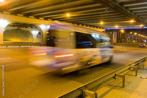 The motion of a blurred minibus under the bridge in the evening.