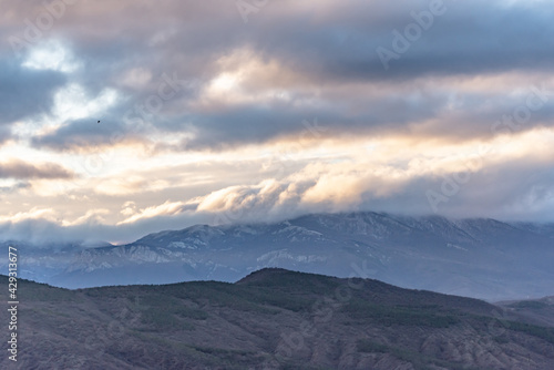 Southern coast of Crimea at sunset in winter. Sunset rays of the sun break through the clouds. Mountains  coast and beautiful scenery.