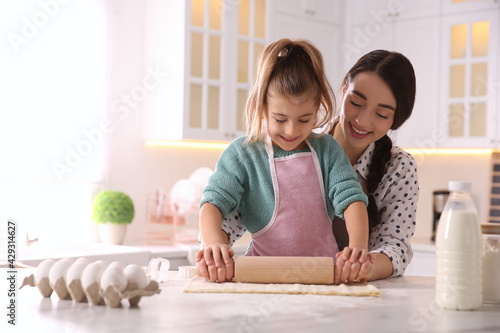 Mother and daughter rolling out dough in kitchen at home
