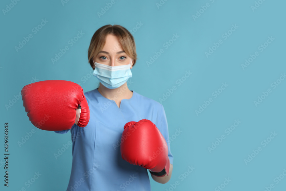 Doctor with protective mask and boxing gloves on light blue background, space for text. Strong immunity concept Doctor with protective mask and boxing gloves on light blue background, space for text. Strong immunity concept